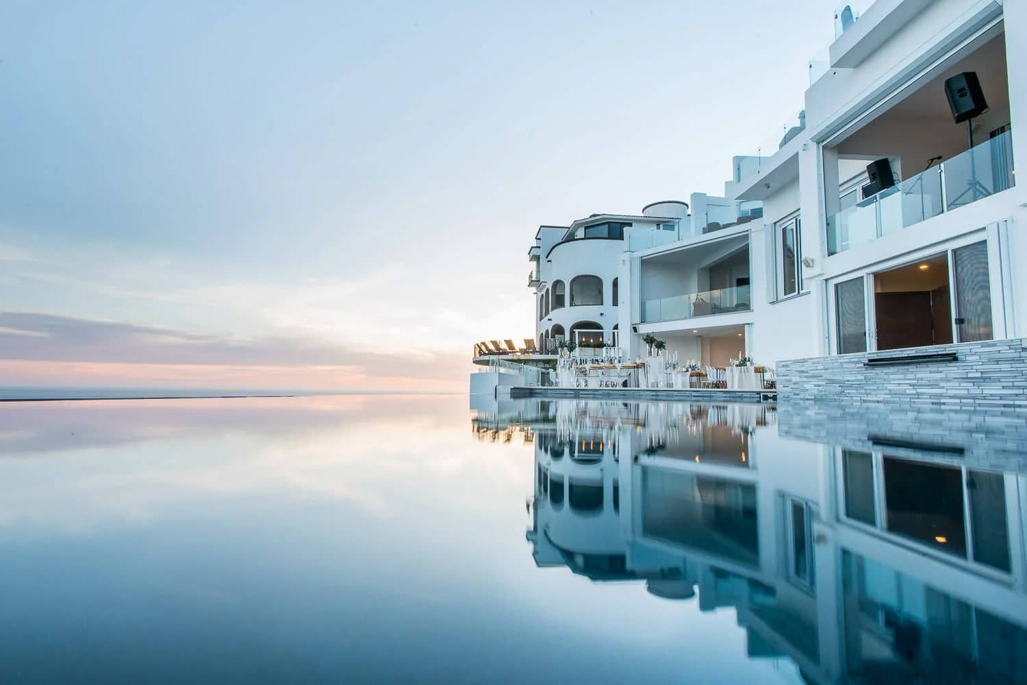 Twilight cabo wedding reception at Villa Lands End in Pedregal, Cabo San Lucas, with white-linen tables beside the infinity pool