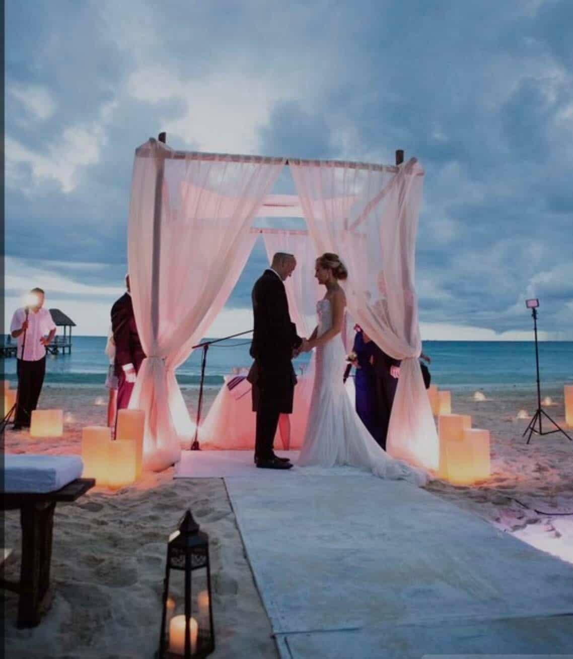 Bride and groom exchanging vows at a Casa Mareva cabo wedding under a draped canopy on the sand at dusk
